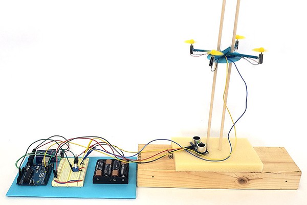 Mini drone hovering on guide poles next to Arduino and control circuit