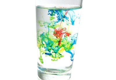 A glass of water with food coloring burst under water.