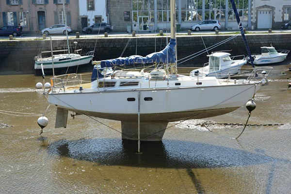 Low tide reveals a large fin attached to the bottom of a sailboat