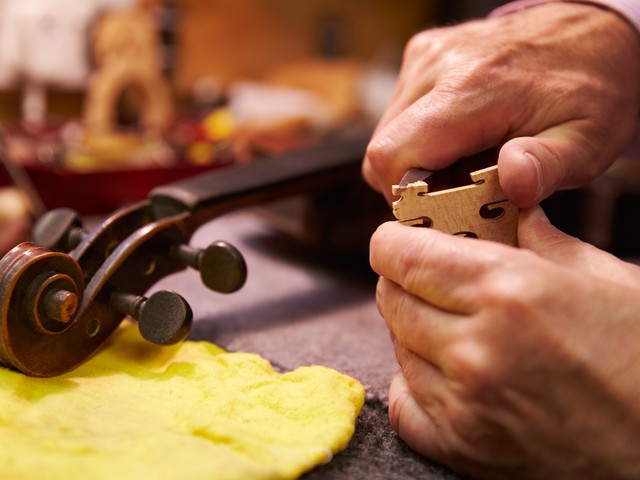 man repairing violin in woodshop