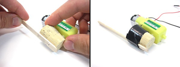 A popsicle stick is taped to the side of a cork which is attached to a DC motor