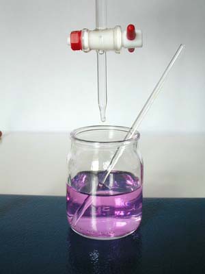 Purple translucent liquid in a glass jar underneath a buret