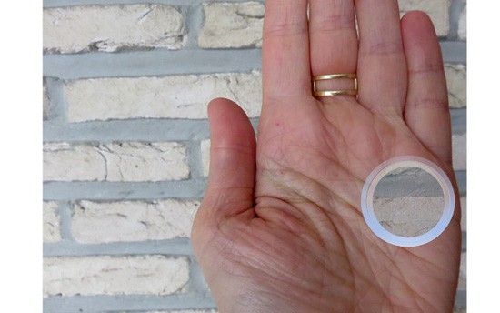 Photo of a brick wall visible through a hole in a person's hand
