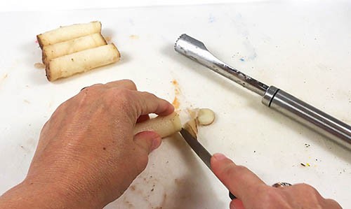 The potato strips are trimmed with a knife.