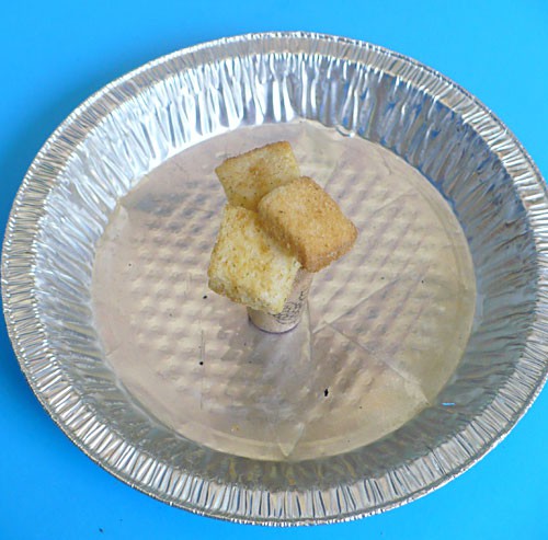 Three pieces of bread are skewered with needles to hold them together