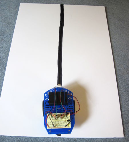 A line-following robot is placed on a white paper with a large black line drawn straight across