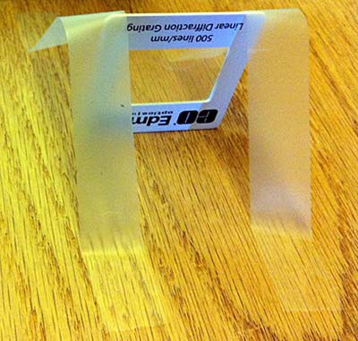 Clear tape used to secure a small diffraction grating upright on a tabletop so light can pass through unobstructed