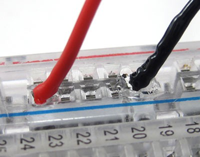 Close-up photo of melted plastic and insulation where a wire connects to a breadboard