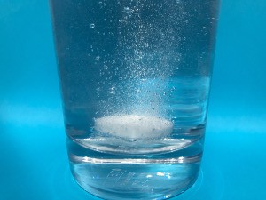 An Alka-Seltzer tablet dissolves in a glass of water