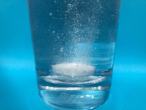 An Alka-Seltzer tablet dissolving in a glass of water