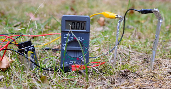 Sample of circuit designed for environmental monitoring sitting in grass and connected to a multimeter