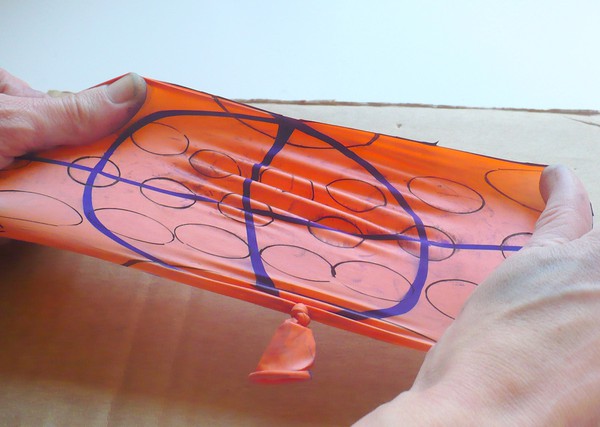 wo hands stretching out the cut open balloon. 
Circles away from the equator are larger than those on the equator. 