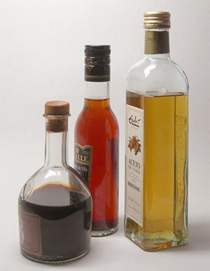 Three bottles of different vinegars, balsamic, red wine and white wine