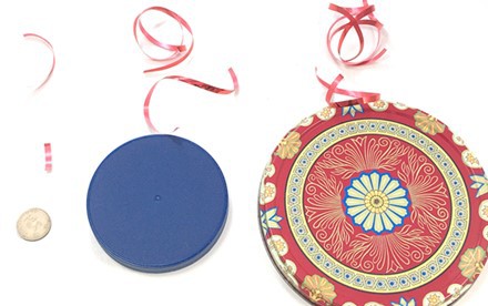 A line of three circular objects arranged from small to large, each with pieces of ribbon next to them. Each circle has a short and a longer piece of ribbon placed next to it. 