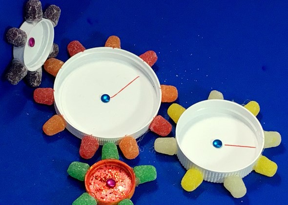 Four interlocking gears made from plastic lids and gumdrops