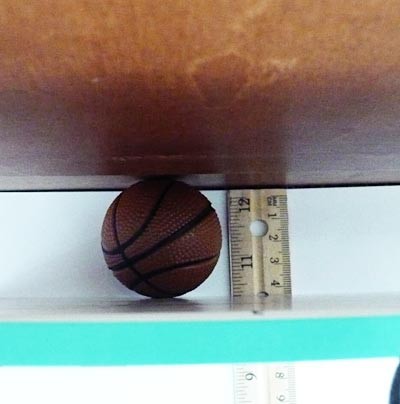 A test basketball is fit between two flat parallel surfaces and its diameter is measured
