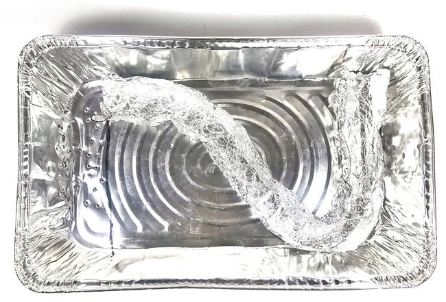 Aluminum pan with a lightly curved aluminum foil river model inside.