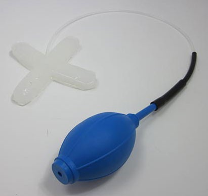 Rubber tubing connects the center of a cross-shaped silicon robot to a squeeze bulb