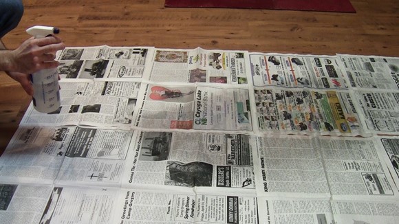 Newspaper with a wet spot several feet in diameter in front of the bottle.