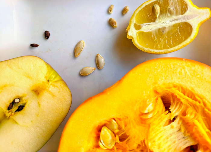 Apple, pumpkin, and lemon cut in half with seeds from each