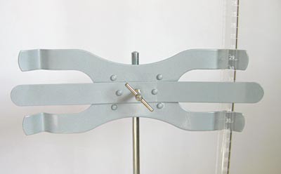 A glass buret is held between the three metal prongs of a buret clamp