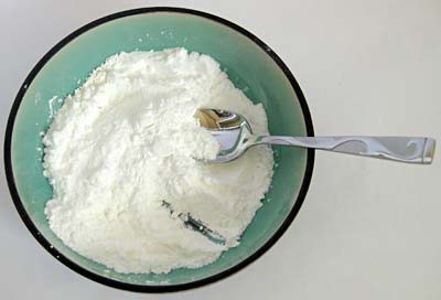 Fine white powder is mixed in a bowl with a spoon