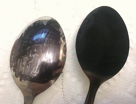 Two spoons: the left shiny with permanent marker colored on it, the right covered in soot