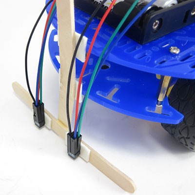 Popsicle sticks and double side tape are used to mount IR sensors to the front of a line-following robot