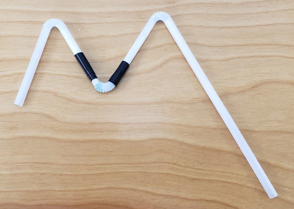 An M shape made from three straws, with the connections wrapped in electrical tape. 