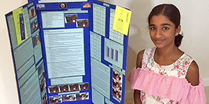 A student standing in front of a science fair display board