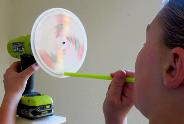 A straw is pointed at a spinning disk that is attached to a drill bit