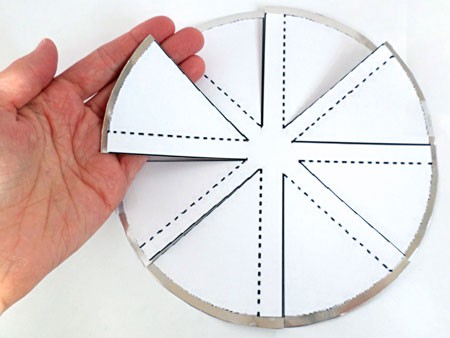 Cuts are made to an aluminum circle following a paper windmill template that is taped on