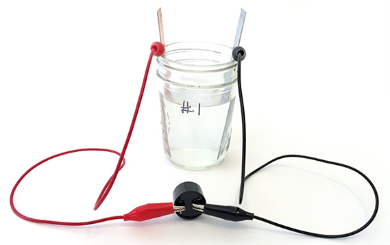 physics experiments electricity A saltwater zinc-air battery made from a jar, electrodes, and alligator clips