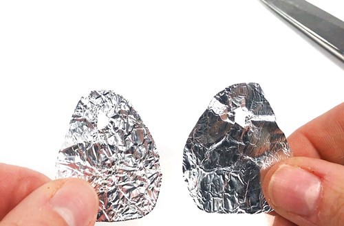Two tear-shaped aluminum pieces with a small hole at their tops.