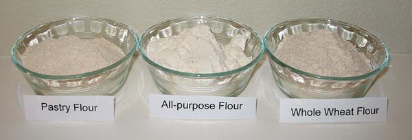 Three small bowls side-by-side filled with different types of flour