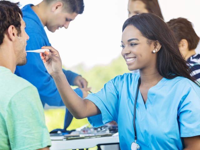 person taking another person's temperature in a temporary clinic