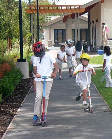 Children riding scooters on a sidewalk