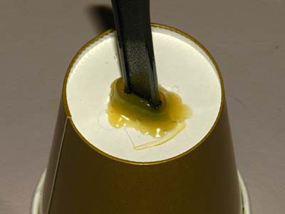 A plastic knife is inserted into the bottom of a paper cup and glued in place