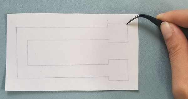 Using a straightedge, to help cut around the edges of the traced shape. 