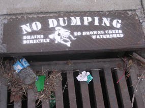 A storm drain grate with a no dumping sign painted on
