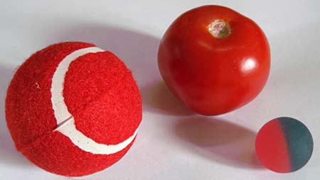A red tennis ball, red apple and rubber ball rest side-by-side