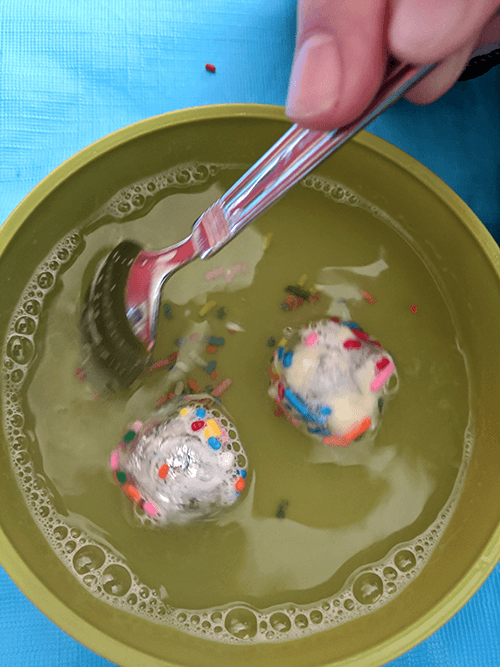 Student stirring a bowl of soap and water in which the virus models are floating