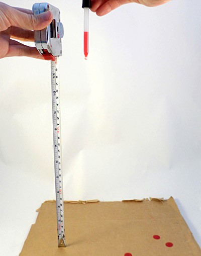 A medicine dropper is used to drop a red liquid onto cardboard from specific heights