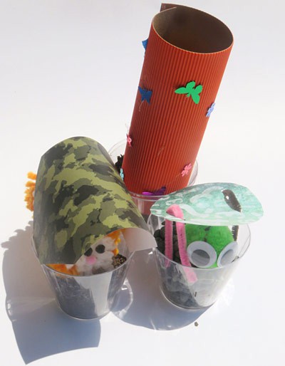 Toy animals sit in cups with coverings over their heads