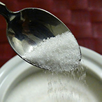 Spoon dropping sugar into a cup