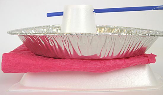 A folded square of pink tissue paper lays between a homemade electroscope and a styrofoam lid