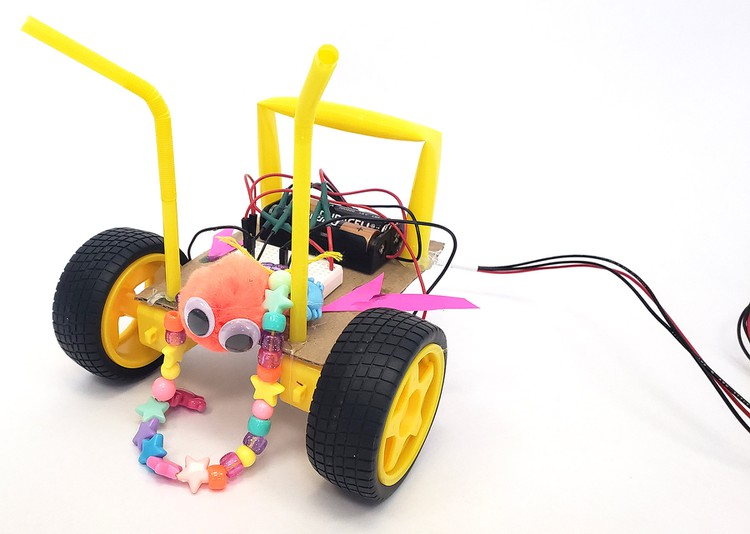 A completed robot decorated with googly eyes, straw antennae, and a bead necklace.  