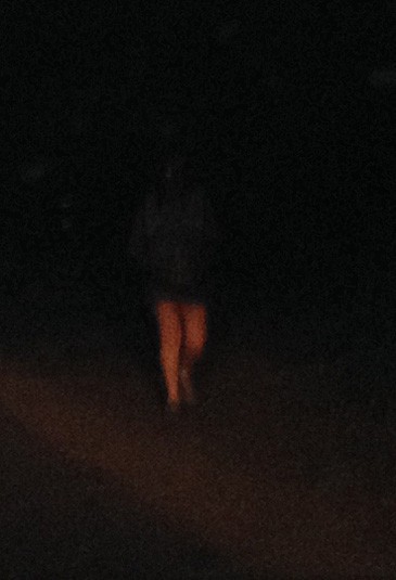 Photo of a jogger barely visible in the dark