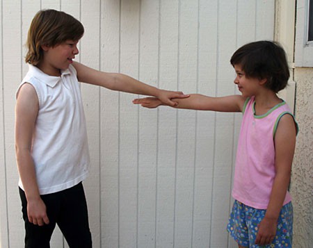 Photo of a child pressing down on the extended arm of another child