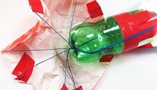 A plastic parachute attached with suspension lines that come together in the center of the top of a bottle rocket.   